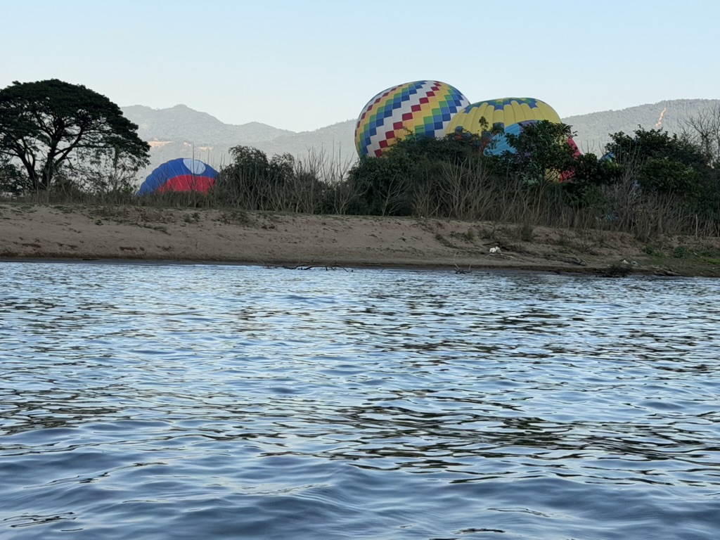ヴァンヴィエン郊外の川岸でカラフルな熱気球が地面に展開中