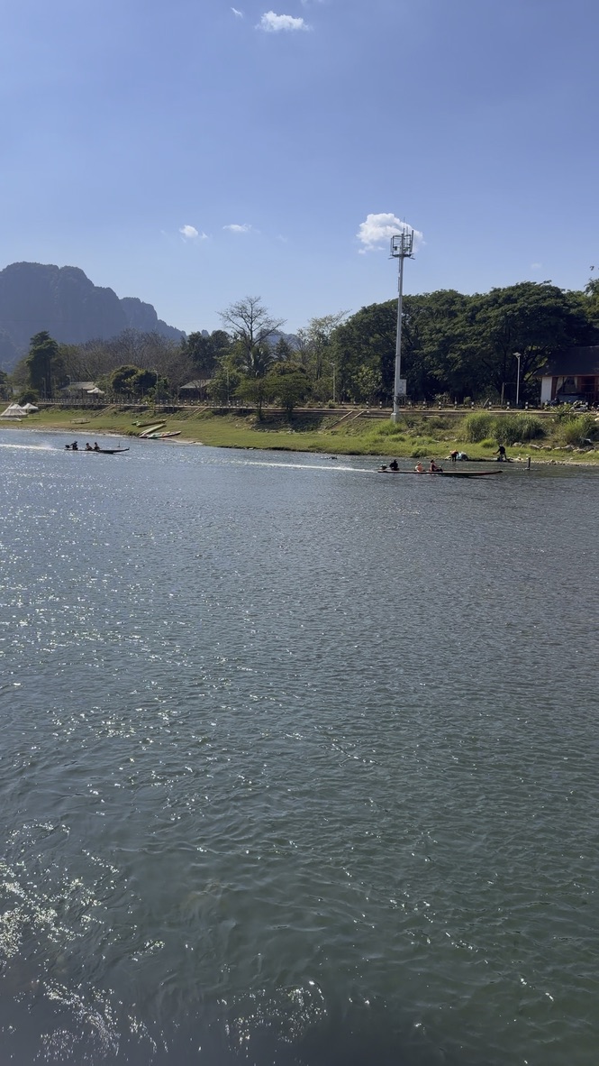 ヴァンヴィエンのナムソン川とカルスト地形の山々、川にはボートが浮かんでいる