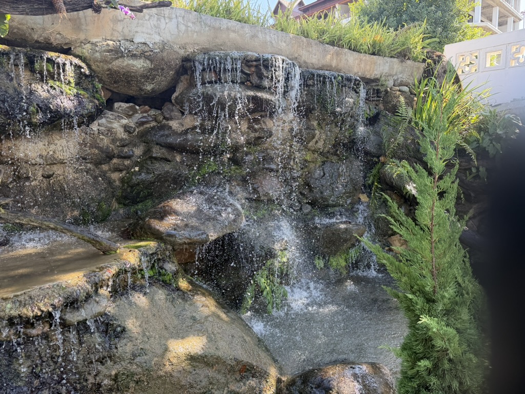ビエンチャン近郊の庭園にある苔むした岩場の小滝