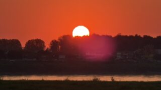 メコン川の対岸に沈む鮮やかな赤とオレンジの夕日
